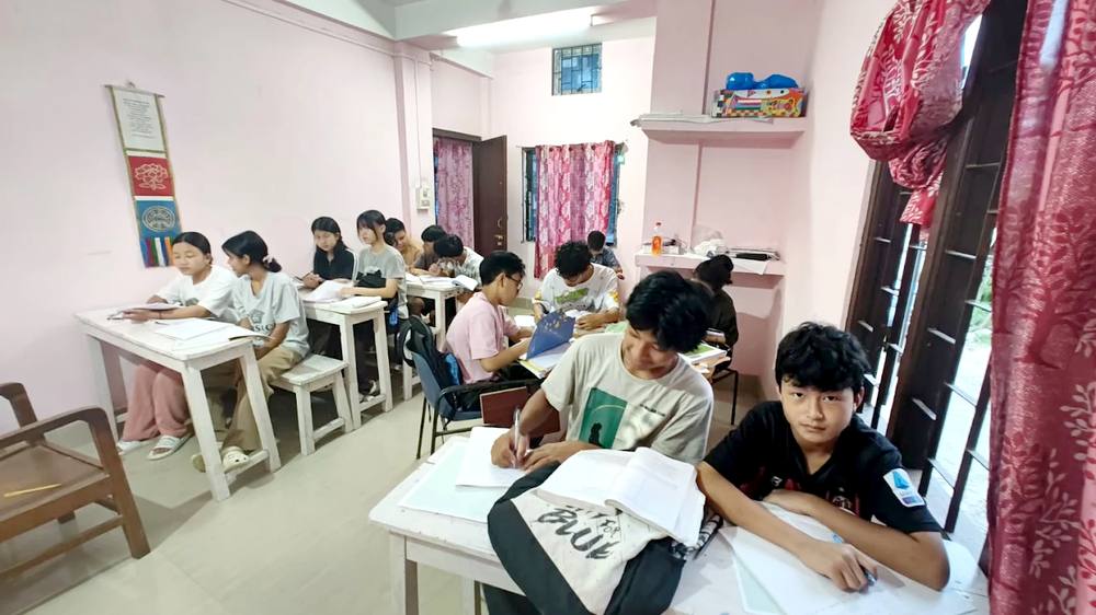 Students seated at desks writing in notebooks during a class at Omega Tutorial