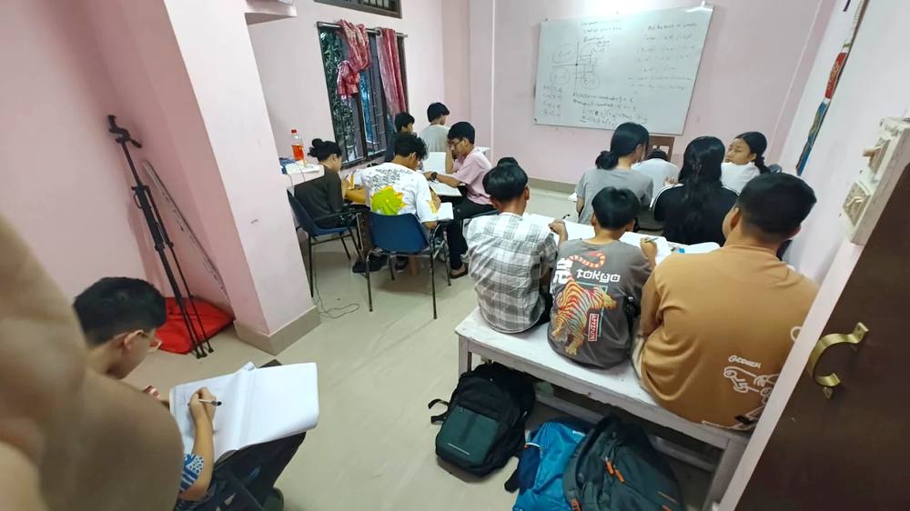 Students taking notes in front of a whiteboard filled with maths problems