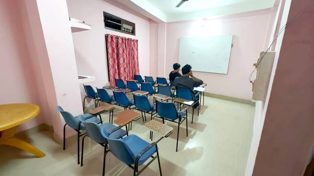 Empty classroom with rows of chairs facing a whiteboard, set up for the next batch
