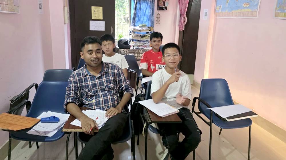A mentor sitting with students, smiling for a photo during class
